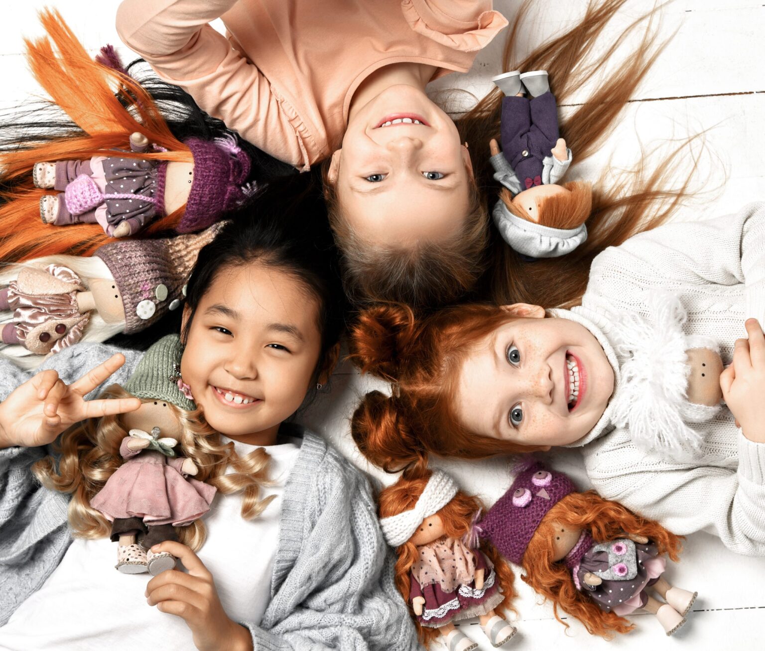 Smiling happy girls with healty teeth laying on the floor with toys